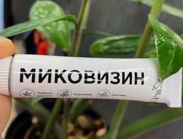 Тюбик крема Миковизин на фоне цветка.